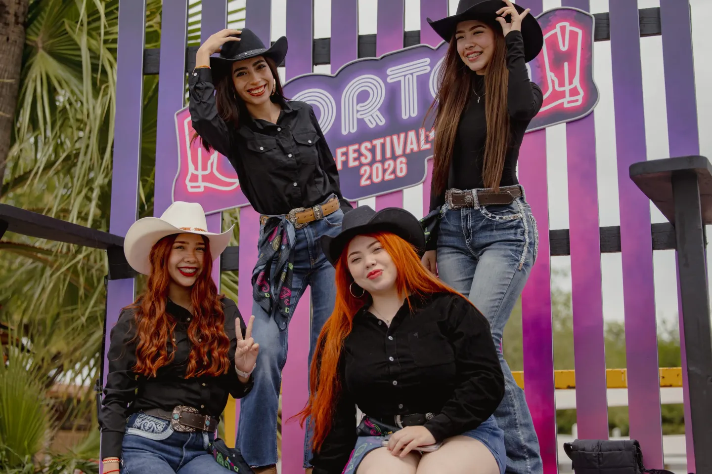 Grupo de asistentes posando frente a un mural del festival
